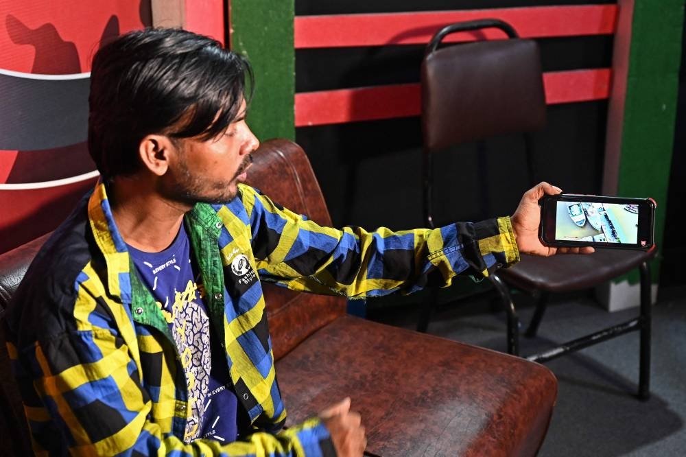 In this picture taken on August 3, 2022, YouTuber Hero Alom shows a video on his mobile phone during an interview at his office in Dhaka. — AFP pic
