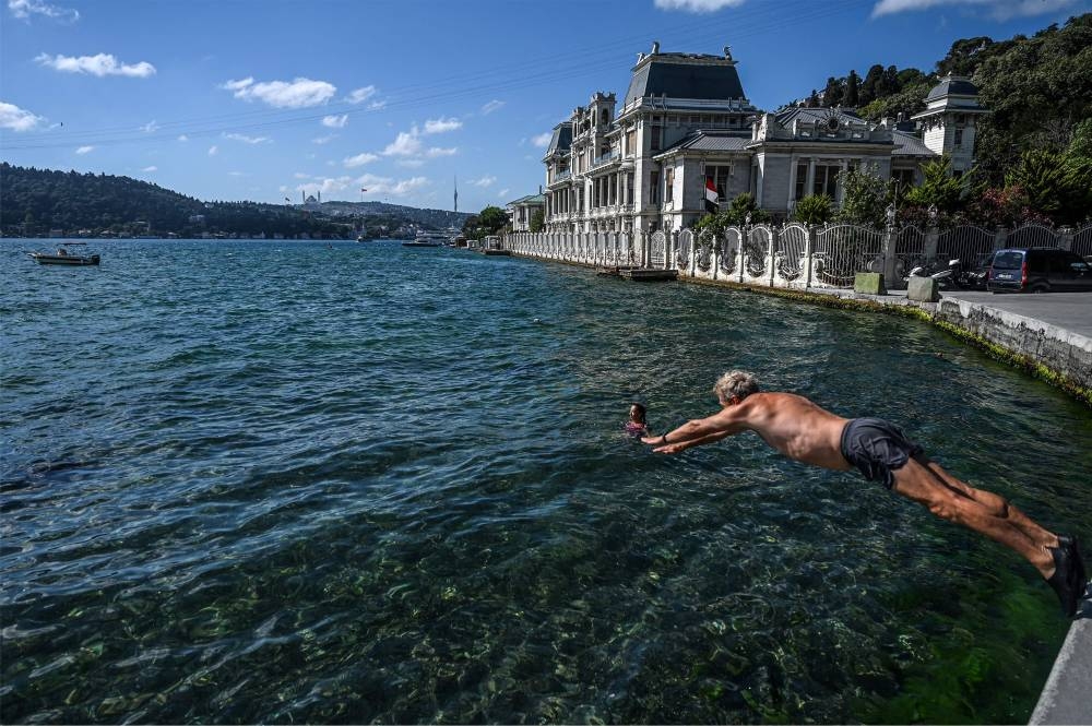 A swimmer dives into the water in the Bosphorus strait in Istanbul's Bebek district on July 29, 2022. — AFP pic
