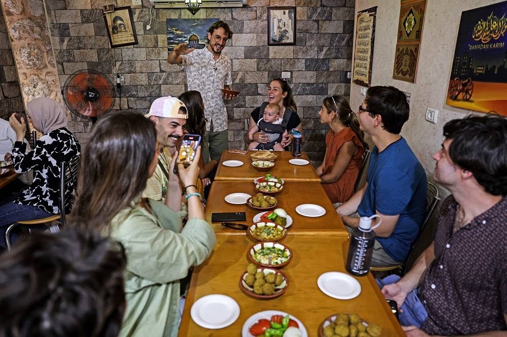 Tourguide Izzeldin Bukhari (centre), who runs Jerusalem food tours and cooking classes, presents dishes to tourists in a restaurant during a guided tour in the Old City. ― AFP pic