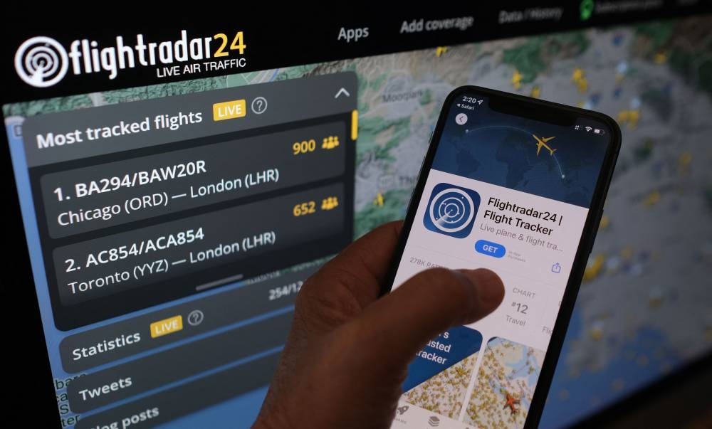 In this illustration photo, the Flightradar24 app is seen on a smartphone in front of a screen showing the live position of planes tracked by the app in the area of Los Angeles, California, on August 5, 2022. — AFP pic