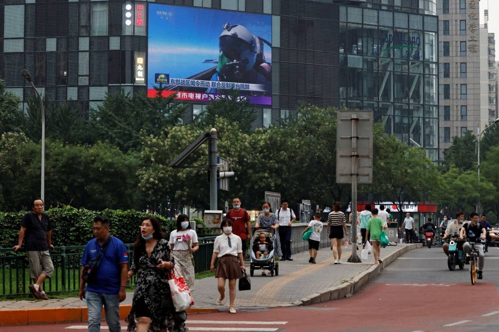 Pedestrians walk past a giant screen broadcasting news report on Chinese People’s Liberation Army’s (PLA) military exercises around Taiwan, in Beijing, China August 4, 2022. — Reuters pic