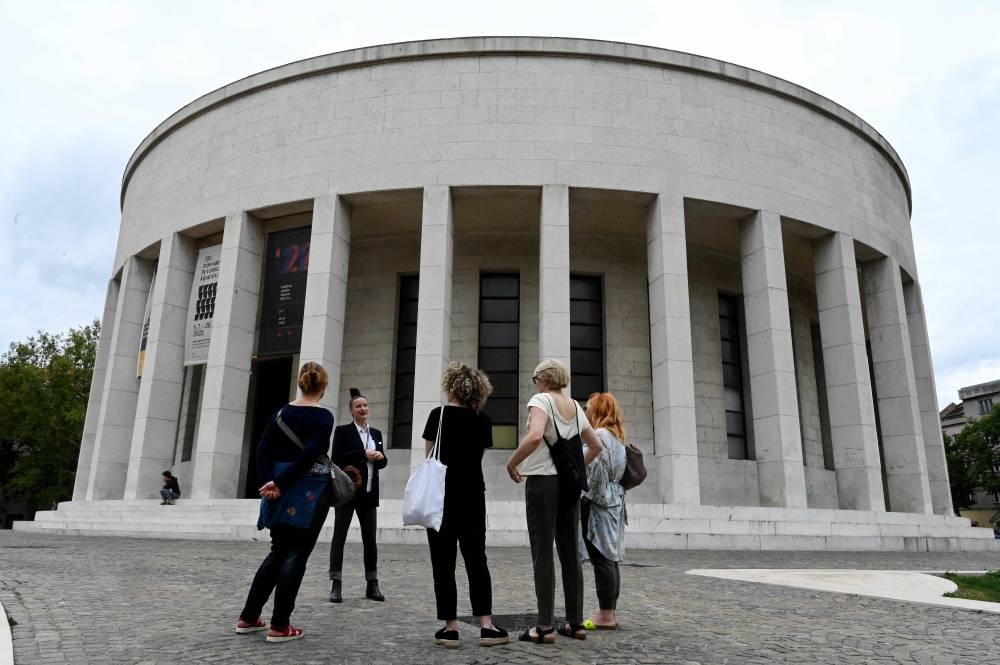 Danijela Matijevic (2nd left) gives explanations in front of the Mestrovic Pavilion, the former Museum of the Revolution, at the start of a walking historic tour telling the story of late Yugoslav leader Josip Broz Tito in Zagreb, Croatia, on July 8, 2022. — AFP pic