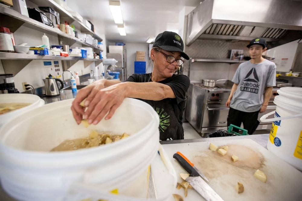 Joanne Manning and Bernard Naulalik demonstrate how they prepare food at the Qajuqturvik Community Food Centre in Iqaluit, Nunavut, Canada July 28, 2022. — Reuters pic