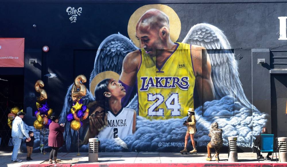 People gather in front of a mural of former Los Angeles Laker Kobe Bryant and his daughter Gianna in downtown Los Angeles January 26, 2021. — Reuters pic