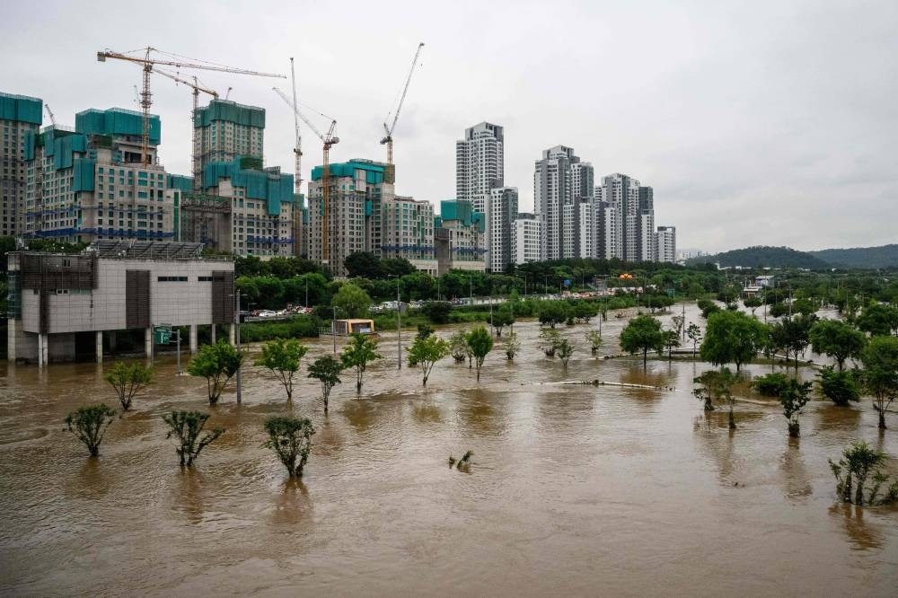 Flood waters flow over a carpark (bottom back) and pedestrianised area that were submerged by the burst banks of the Han River in Seoul on August 10, 2022. — AFP pic