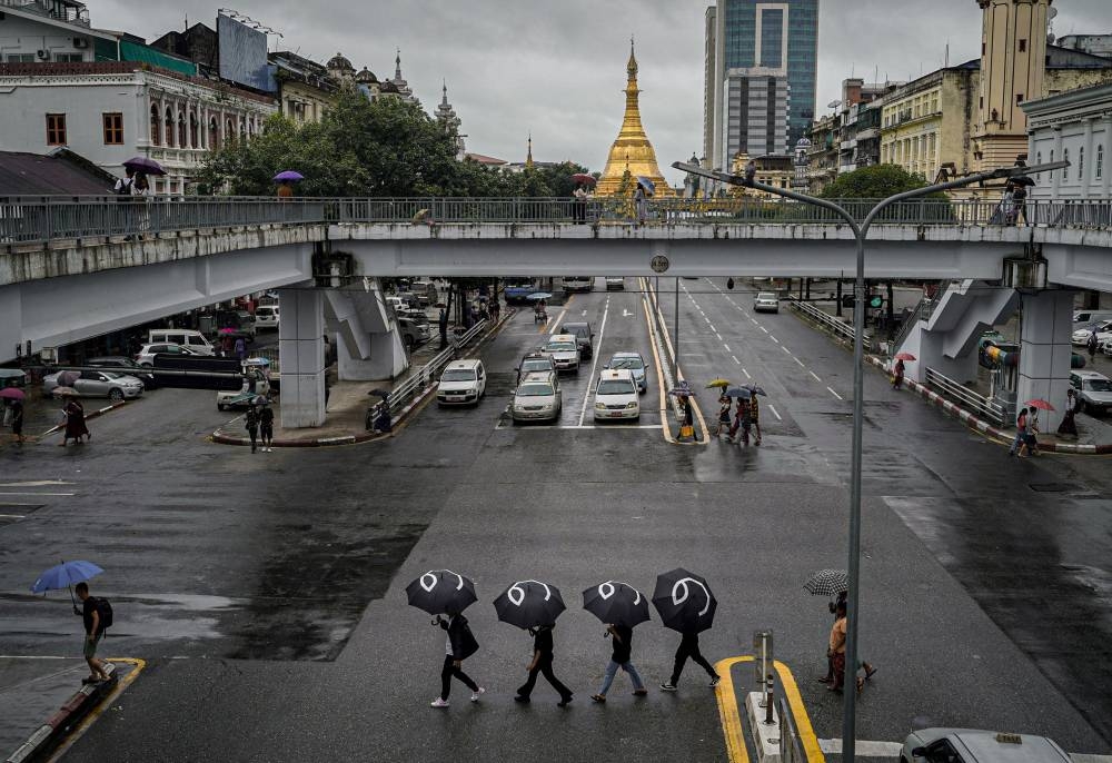 This handout picture taken and released by Yangon People’s Strike on August 8, 2022, shows protesters walking through Yangon with umbrellas bearing in Burmese the number 8 during a rally to mark the anniversary of the August 8, 1988 democracy uprising against a previous junta. — AFP pic