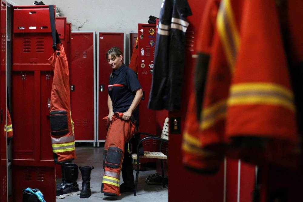 French volunteer firefighter Aurelie Ponzevera puts her gear on in the cloakroom of the Ajaccio’a fire station, in Ajaccio, on the French Mediterranean island of Corsica on August 12, 2022. — AFP pic