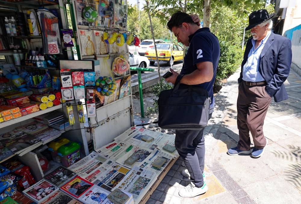 Iranians check newspapers at a ksoque in the capital Tehran on August 13, 2022, a day after a man stabbed British author Salman Rushdie, the target of a 1989 Iranian fatwa calling for his death, during a literary event in New York state. — AFP pic