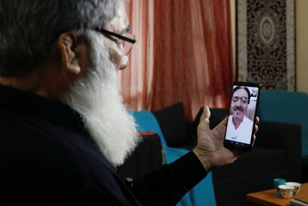 Ali Hassan Baqai, 76, whose family was divided by the partition of the subcontinent in 1947, speaks with his wife Shaistan Ali, as they go through the family picture album, at home in Karachi, Pakistan August 12, 2022. — Reuters pic