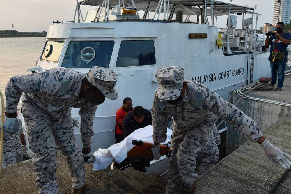 Members of the Malaysian Maritime Enforcement Agency (APMM) together with the police lifting the body of one of the three men who were found drowned after their boat sank near the waters of Redang Island, upon arrival at the Kuala Terengganu Maritime Jetty in Kuala Terengganu, August 10, 2022. — Bernama pic