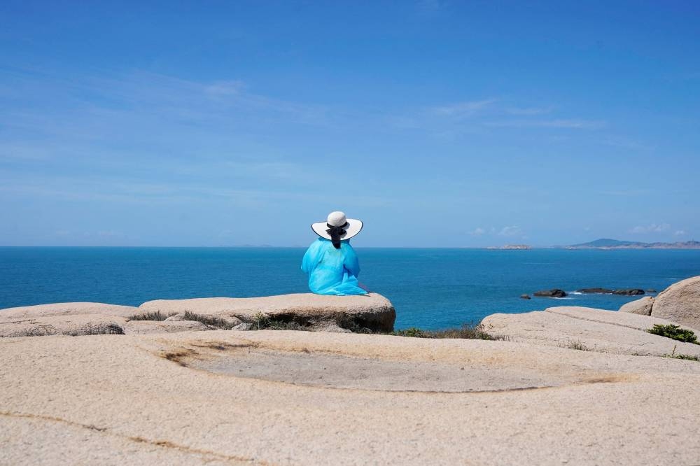 File photo of a tourist sits facing the Taiwan Strait at the 68-nautical-mile scenic spot, one of mainland China's closest points to the island of Taiwan, in Pingtan island, Fujian province, China August 5, 2022. — Reuters pic