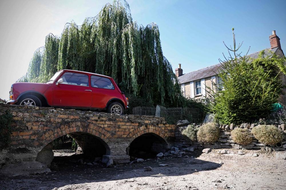 A vintage Mini is parked on the driveway over the dry river bed of the Infant River Thames, in Ashton Keynes, on August 8, 2022. According to villagers of Ashton Keyes, they had only seen the river dry in that area once before, in 1976. The source of the Thames has dried up and has shifted more than five miles downstream from Thames Head near Cirencester in Gloucestershire. Swathes of southern and eastern England recorded the lowest rainfall in July 2022 on record, the UK's Met Office. The whole of England recorded an average of 23.1 mm of rain —  the lowest figure for the month since 1935 and the seventh lowest July total on record, it said. — AFP pic