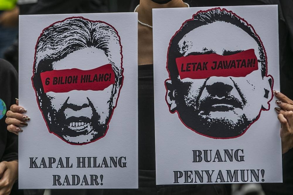 A protestor holds up placards to protest the military asset procurement scandal outside the Sogo shopping centre in Kuala Lumpur August 14, 2022. — Picture by Hari Anggara
