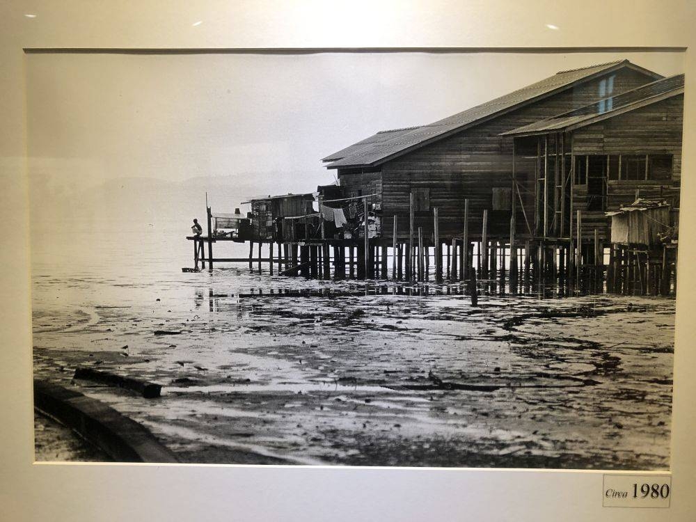 A man squatting at an outdoor toilet which is a hole in the planks at the edge of the jetty back in 1979. — Picture courtesy of Dr Ooi Cheng Ghee