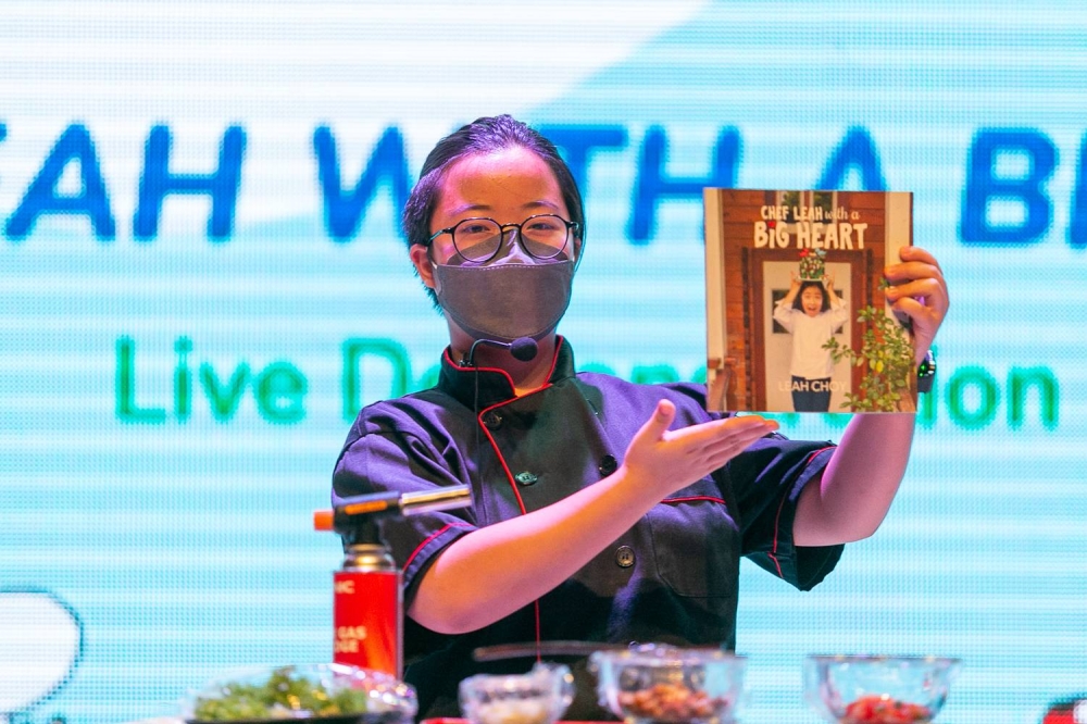 Choy holds up her debut book Chef Leah With A Big Heart during her cooking demonstration at KidZania Kuala Lumpur. The teen says she has two more books in the works. — Picture by Devan Manuel
