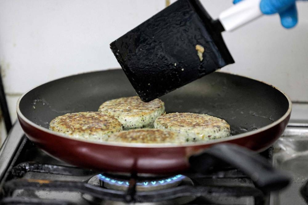 In this file photo taken on June 08, 2022 a worker cooks salicornia plant-based burger patties in a pan at a food processing plant in the Gulf emirate of Sharjah. — AFP pic
