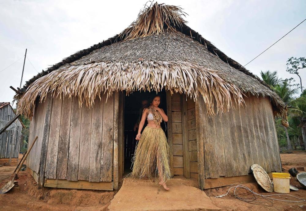 In this file photo taken on August 30, 2019 a young woman from the Uru Eu Wau Wau tribe gets out from a straw-thatched hut in the tribe's reserve in the Amazon, south of Porto Velho, Brazil. — AFP pic
