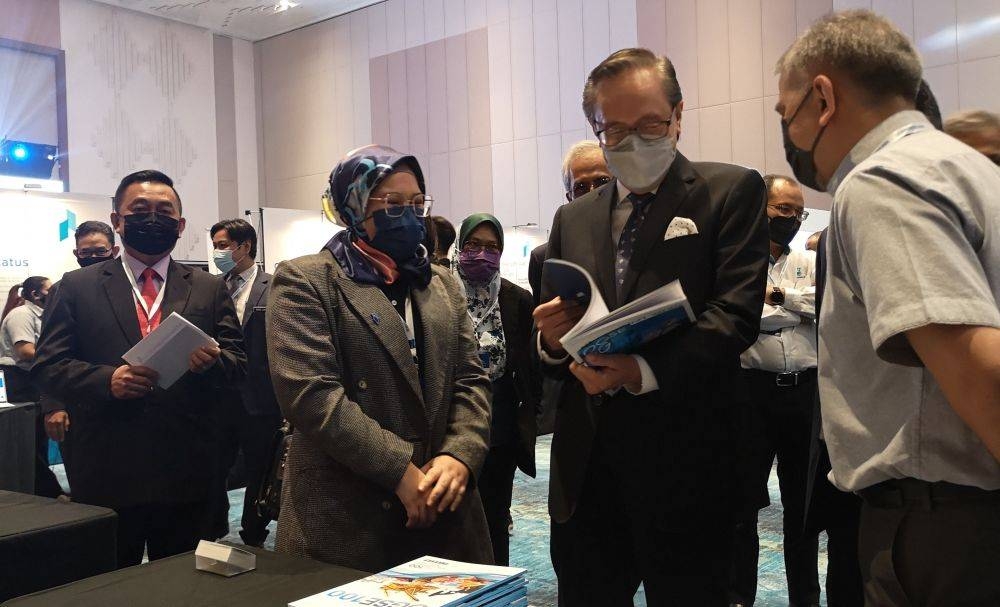 Masidi (second from right) going through the OGSE100 book which features the top 100 OGSE companies in Malaysia. — Borneo Post pic