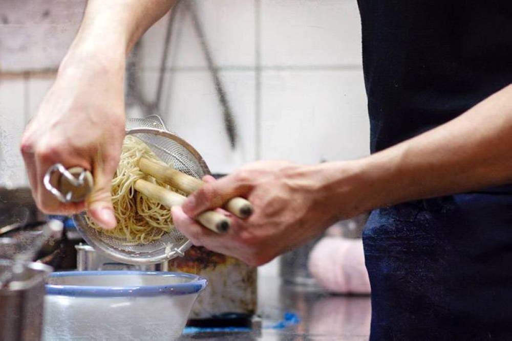 Shaking water from the cooked noodles at a 'ramenya'  in Japan.