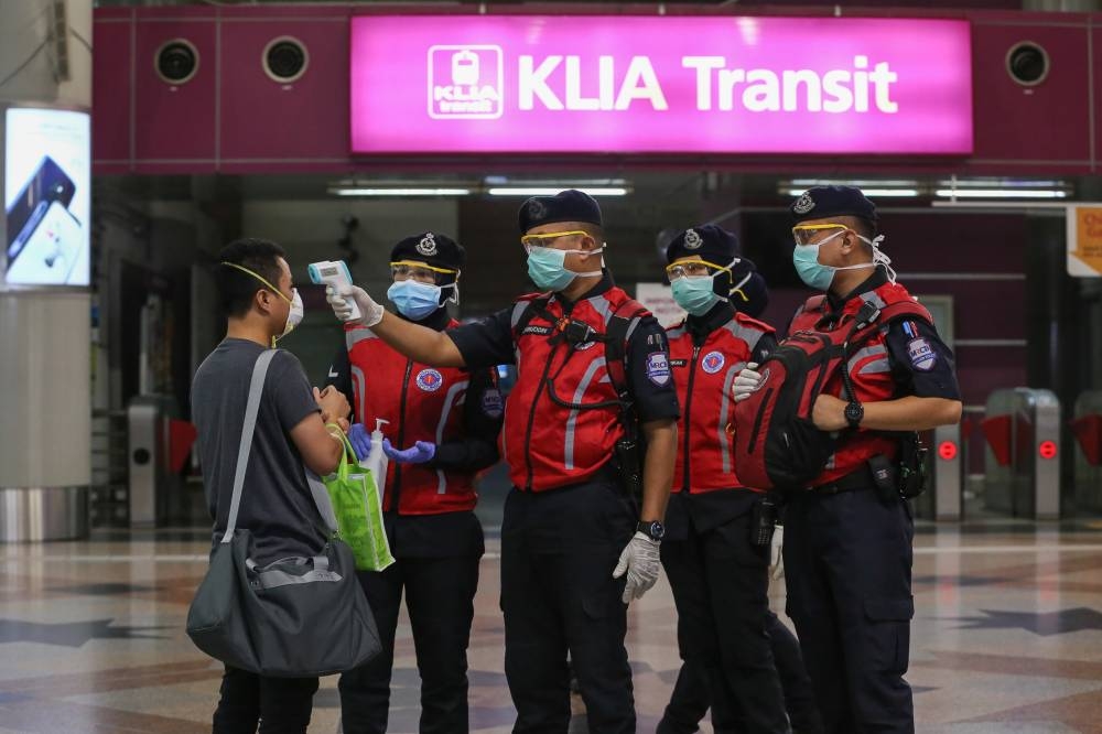 MRC 辅助警察应急响应小组于 2020 年 3 月 20 日在 KL Sentral 检查体温并向公众分发洗手液 — 照片作者 Yusof Mat Isa