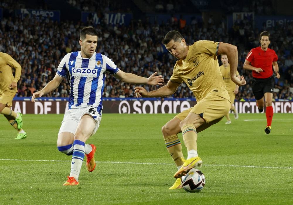 Real Sociedad's Igor Zubeldia in action with FC Barcelona's Robert Lewandowski (right) at Anoeta Stadium, San Sebastian August 21, 2022. — Reuters pic 