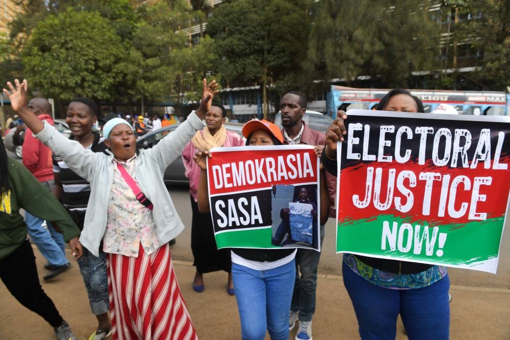 Supporters of Kenya's Azimio La Umoja Party (One Kenya Coalition Party) presidential candidate Raila Odinga hold placards outside the Milimani High Court in Nairobi on August 22, 2022,as they wait to file a petition against the result of the recent general election. — AFP pic