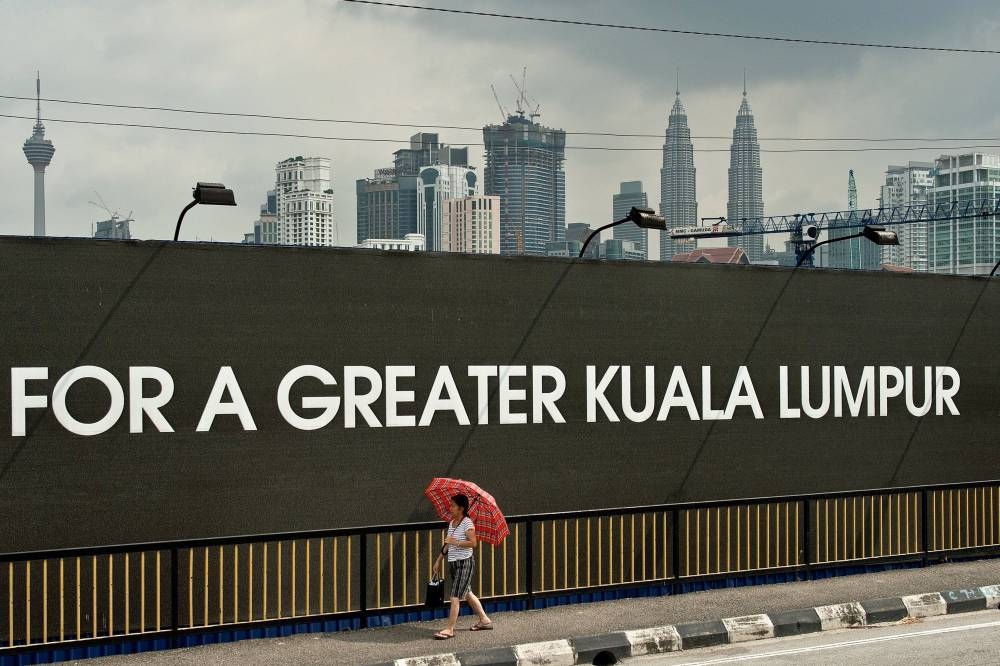 A woman walks past the construction site of the 1Malaysia Development Berhad (1MDB) flagship Tun Razak Exchange in Kuala Lumpur in this file picture taken July 3, 2015. — AFP pic 