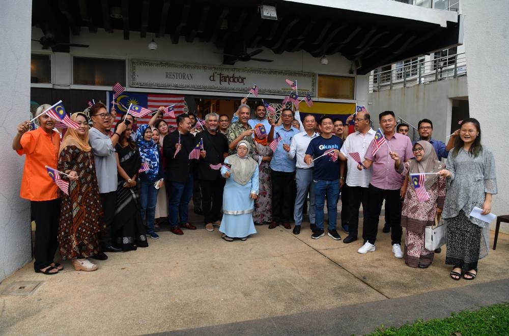 Deputy Domestic Trade and Consumer Affairs Minister Datuk Rosol Wahid (7th, left) waves the Jalur Gemilang during a National Day celebration with Down Syndrome children at D’Tandoor North Indian restaurant in Putrajaya, August 26, 2022. — Bernama pic 