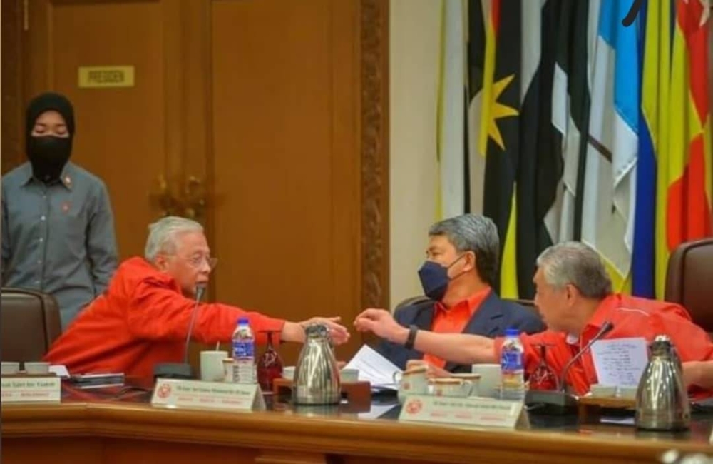 Datuk Seri Ismail Sabri Yaakob and Datuk Seri Ahmad Zahid Hamidi shaking hands during the Umno Supreme Council meeting in Kuala Lumpur, August 27, 2022, as Datuk Seri Mohamad Hasan looks on. — Picture courtesy of the Prime Minister’s Office