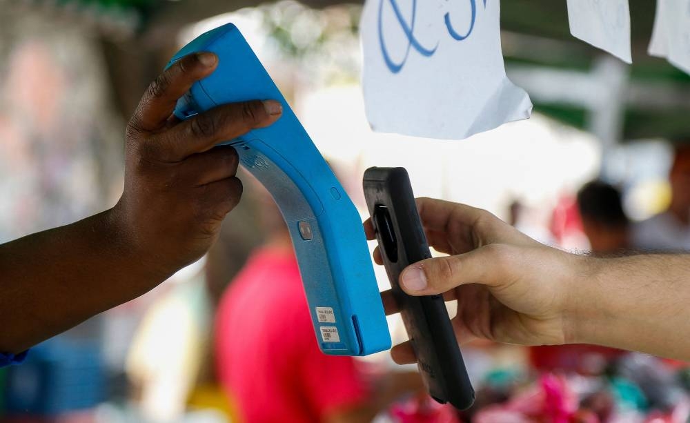 A customer pays by contactless payment at a vegetables stall at the street market in Sao Paulo August 25, 2022. — AFP pic