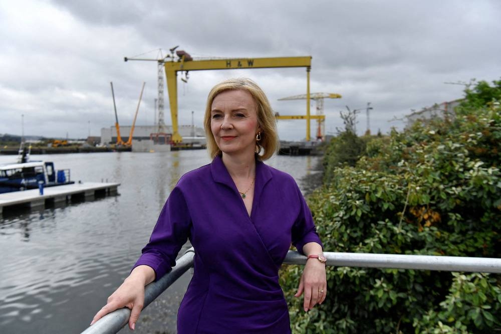 Contender to become the country's next Prime minister and leader of the Conservative party British Foreign Secretary Liz Truss (centre) poses for a photograph with the Harland and Wolff shipyard cranes at a Conservative Party leadership campaign event, at Artemis Technologies in Belfast Harbour, Belfast August 17, 2022. — Pool pic via AFP 