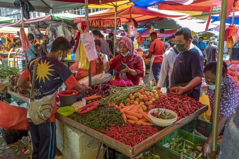 People wearing face masks shop for fresh produce at the Jalan Pudu market in Kuala Lumpur May 17, 2022. — Picture by Shafwan Zaidon