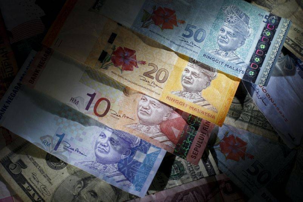 Malaysian ringgit notes of different denominations on top of US dollar notes in this file photo illustration  March 14, 2013. — Reuters pic