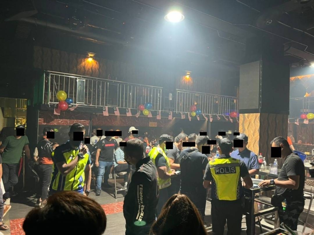 Policemen inspect patrons at an entertainment outlet in Johor Baru, August 31, 2022. — Picture courtesy of Johor police