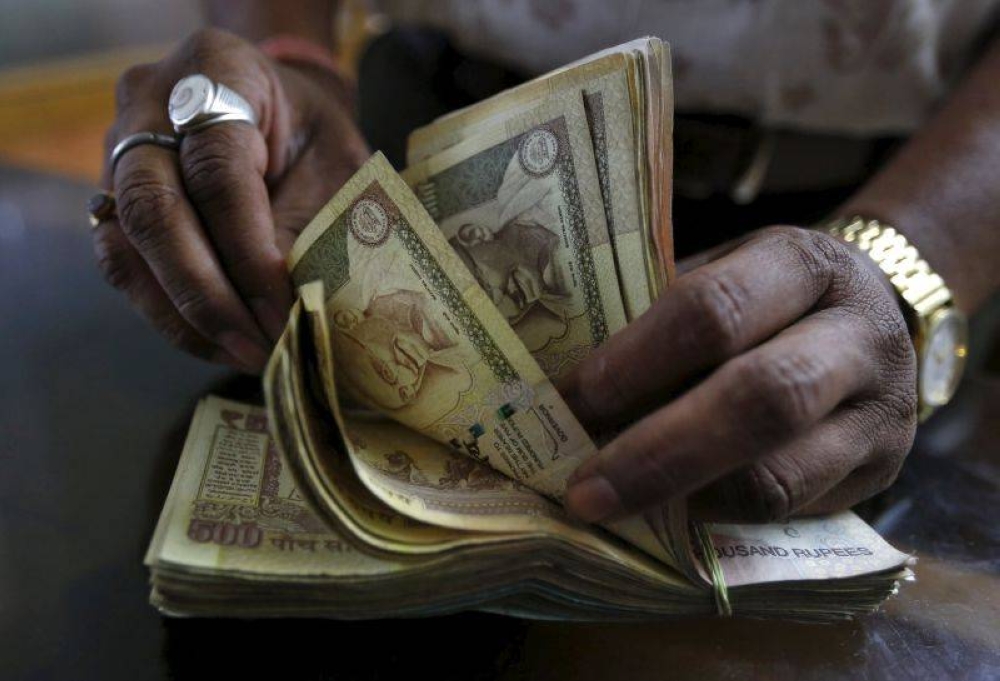 A money lender counts Indian rupee currency notes at his shop in Ahmedabad, India, May 9, 2015. — Reuters pic