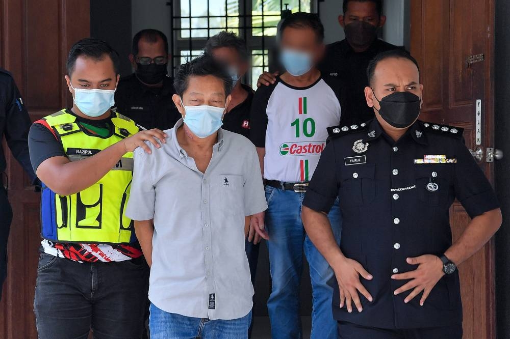 Durian farmer Lee Kok Choong (2nd, left) was brought before the Magistrates’ Court in Bentong today on charges of distributing 841.06kg of methamphetamine last month. — Bernama pic 