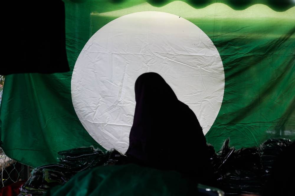 A woman stands in front of the PAS party flag during the 68th Annual PAS Congress (Muktamar PAS) here at Kedah PAS Complex, Kota Sarang Semut. — Picture by Sayuti Zainudin