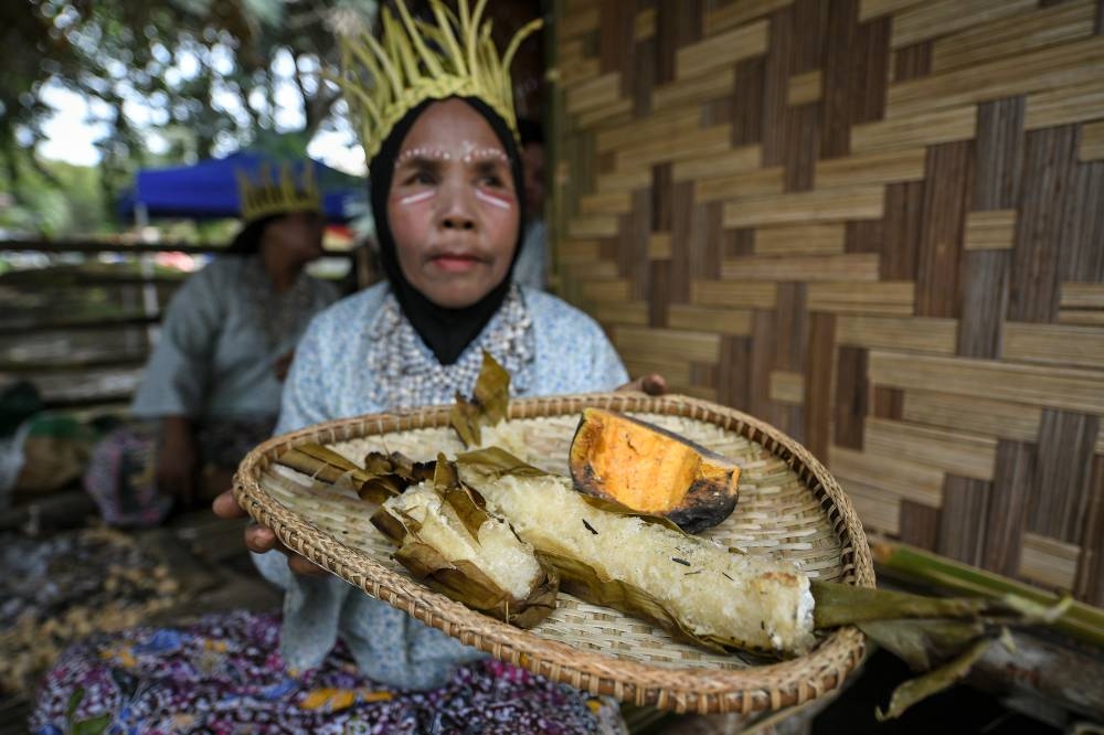 Bedah Alih Osman, 58, from the Temiar Orang Asli tribe shows sweet potatoes and cassava prepared in bamboo to visitors attending the Kedah Malaysian Family Aspiration tour at the grounds of Darul Aman Stadium in Alor Setar September 4, 2022. — Bernama pic