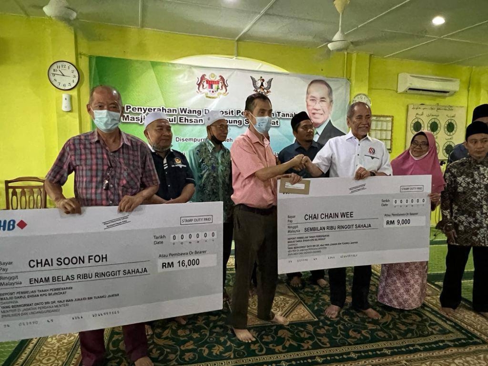 Wan Junaidi (third right) hands over the mock cheque to the landowner. — Borneo Post Online pic