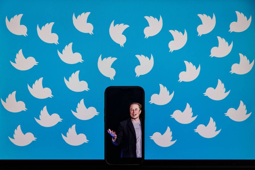 In this file photo taken on August 05, 2022 (FILES) This file illustration photo taken on August 5, 2022 shows a cellphone displaying a photo of Elon Musk placed on a computer monitor filled with Twitter logos in Washington, DC. — AFP pic