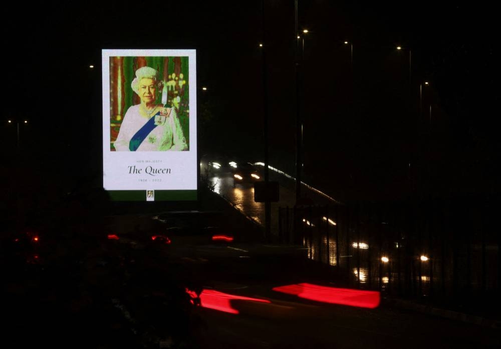 Cars drive past an image of Queen Elizabeth is displayed on a billboard, after Britain's longest-reigning monarch and the nation's figurehead for seven decades, died aged 96, in Edinburgh September 8, 2022. — Reuters pic