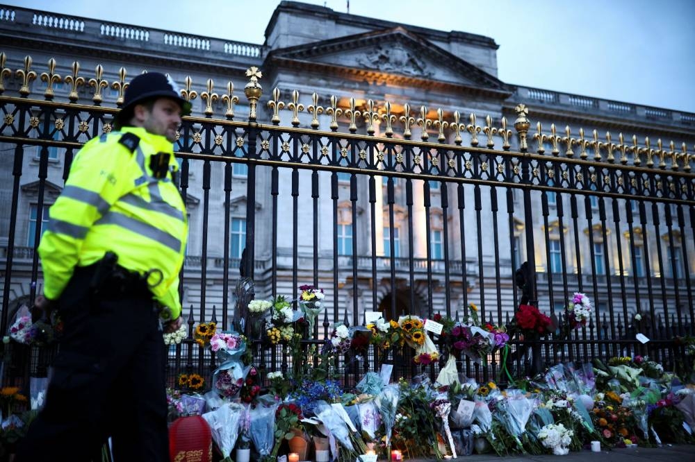 A police officer stands guard near floral tributes placed at Buckingham Palace, following the passing of Queen Elizabeth, in London, Britain September 9, 2022. ― Reuters pic