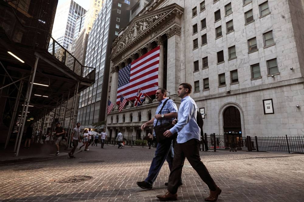 Morning commuters walk on Wall St. as the Union Jack flies at half staff outside the New York Stock Exchange September 9, 2022. — Reuters pic