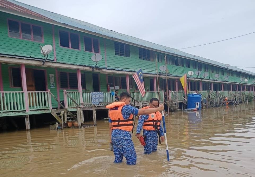 APM personnel monitoring the flood situation at Kampung Mokeng Gudang Bawah. — Borneo Post pic
