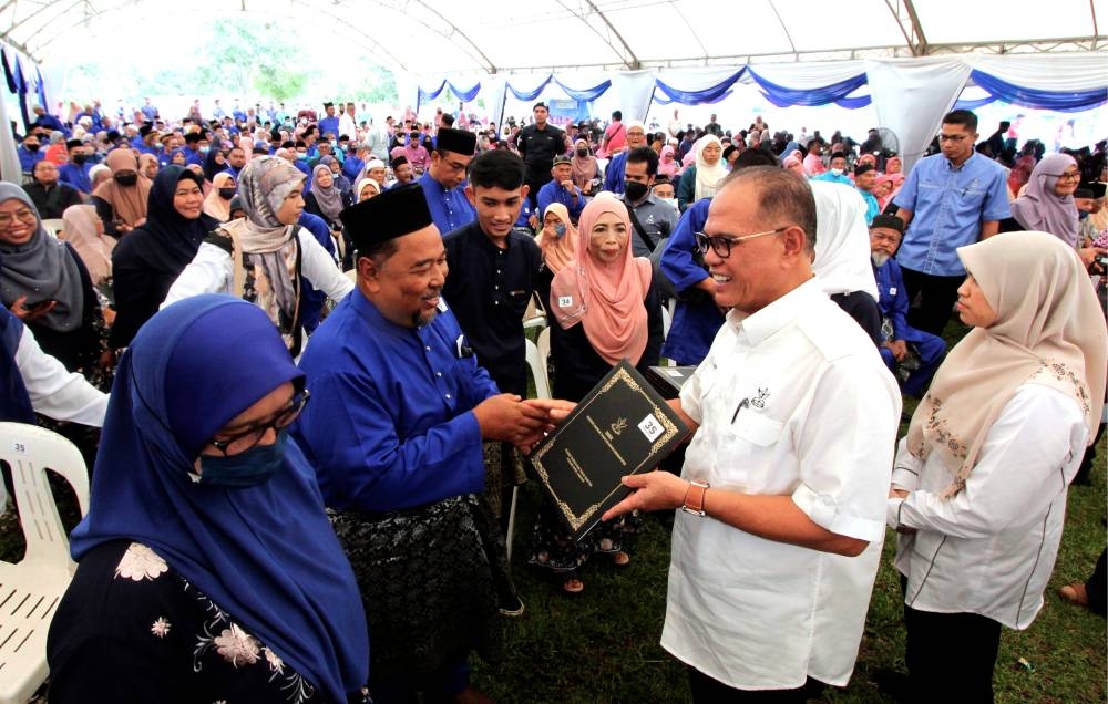 Pahang Mentri Besar Datuk Seri Wan Rosdy Wan Ismail (2nd right) handing over land title deeds to one of the 676 Felda Bukit Sagu 1, 2 and 3 settlers at Dewan Semai Bakti Felda Bukit Sagu 1 in Kuantan September 11, 2022. — Bernama pic