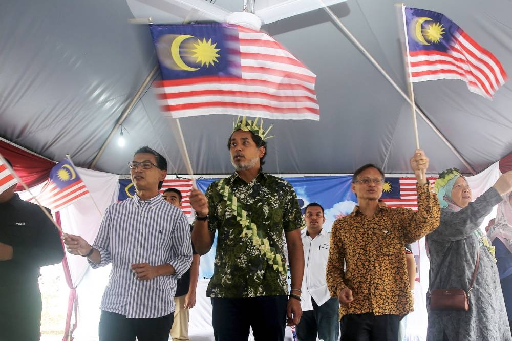 Health Minister Khairy Jamaluddin and Negri Sembilan Information Department director Zaaba Abu Bakar (2nd right) wave the Jalur Gemilang during the Merdeka@Parlimen Rembau programme at the Kampung Seri Kendong community hall in Rembau September 11, 2022. — Bernama pic