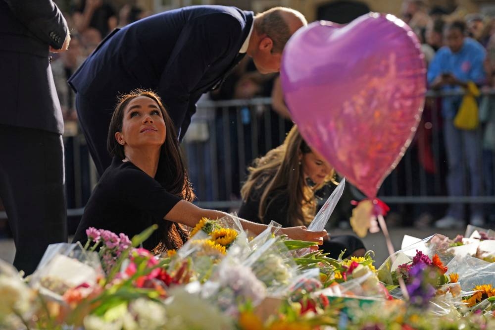 Britain's Catherine, Princess of Wales, Britain's Prince Harry and Meghan, the Duchess of Sussex, look at floral tributes laid by members of the public at Windsor Castle, following the passing of Britain's Queen Elizabeth, in Windsor September 10, 2022. — Kirsty O'Connor/PA Wire/Pool pic via Reuters