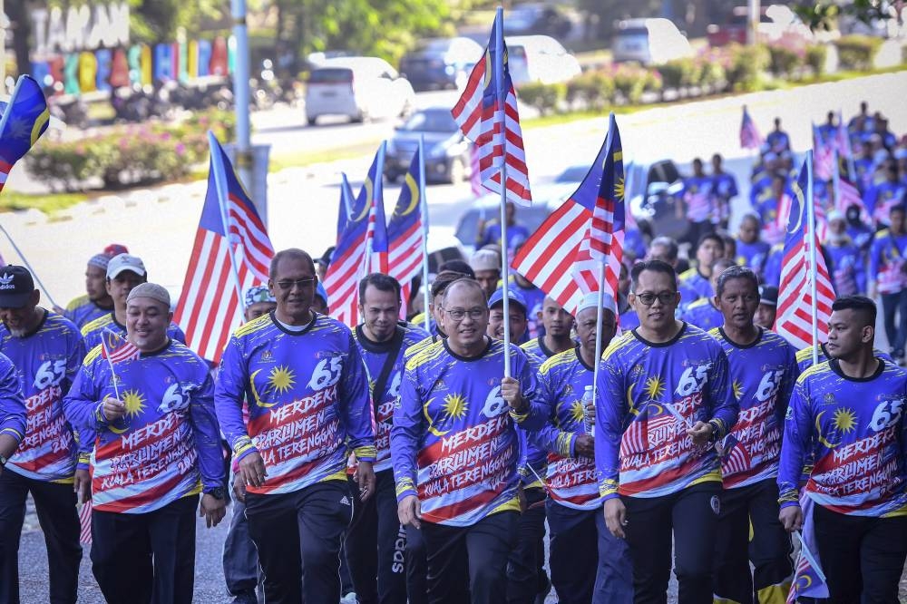 Deputy Minister of Science, Technology and Innovation Datuk Ahmad Amzad Hashim (centre) with participants begin their journey up the hill carrying the Jalur Gemilang in Bukit Besar, Terengganu, September 13, 2022. — Bernama pic 