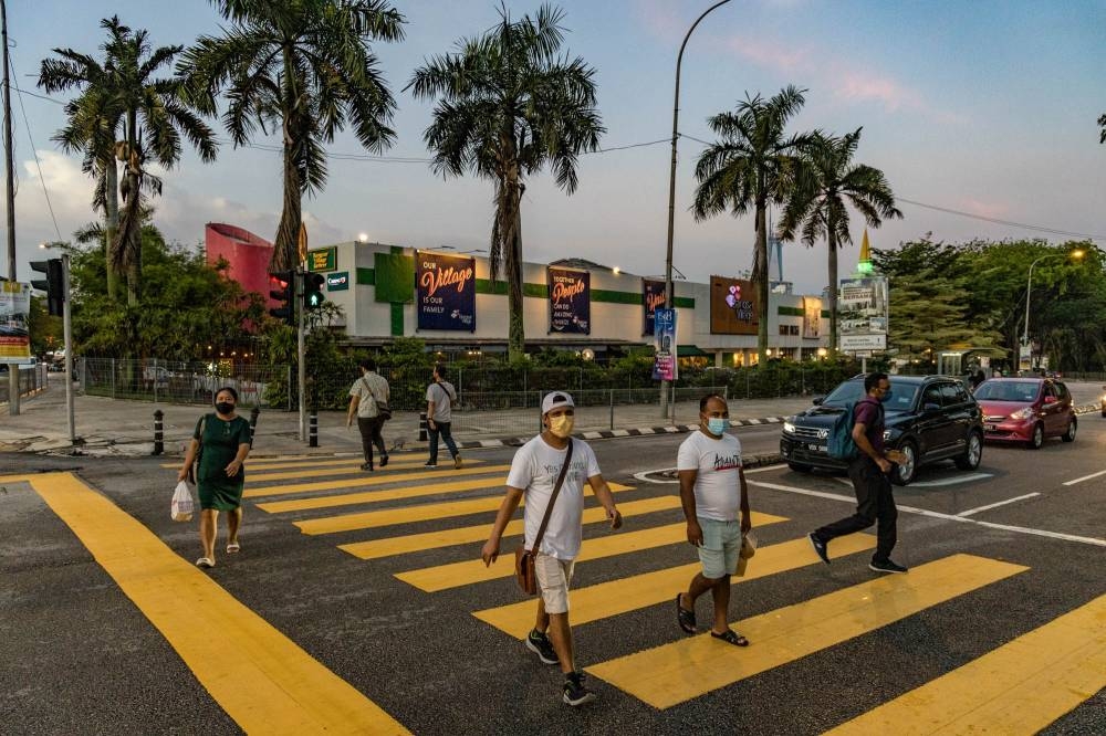 People wearing face masks walk on the street in Bangsar, March 29, 2022. — Picture by Firdaus Latif