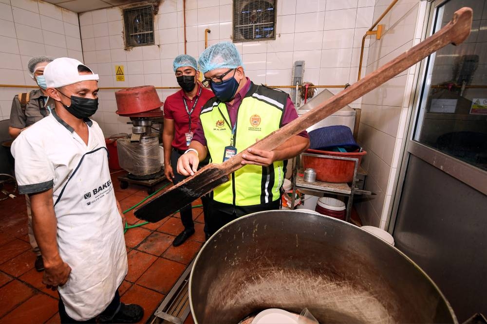 Sandakan Health officer Dr Johari Awang Besar (right) at a hygiene and health inspection operation at a bread and cake factory in Sandakan, Sabah, September 13, 2022. — Bernama pic 